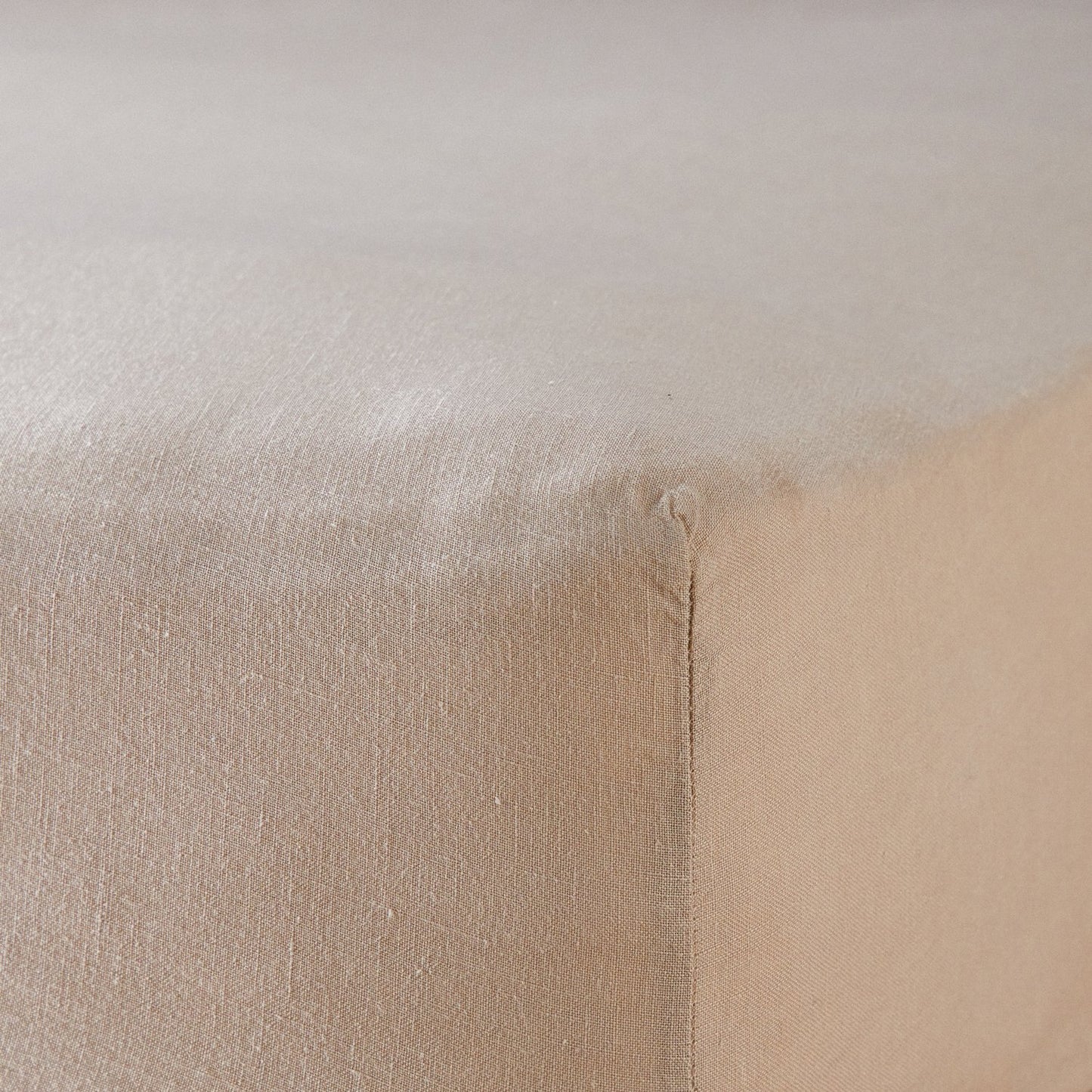 A close up of the corner of a mattress with Woolroom's Mariana Linen Blend Fitted Sheet in Sand.