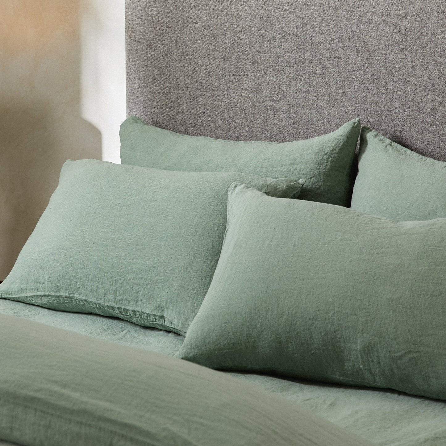 Four pillows on a dressed bed with the Mariana Linen Blend Pillow Cases in Sage.