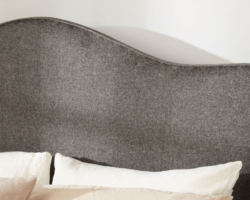 Gray upholstered headboard with white pillows on a bed