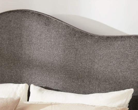 Gray upholstered headboard with white pillows on a bed