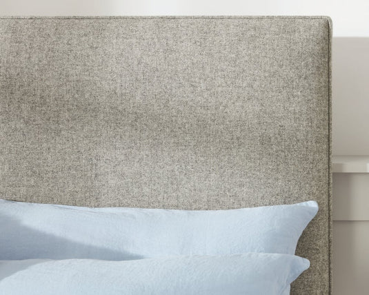 Textured headboard with light blue pillows on a bed.