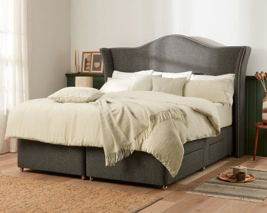 Gray upholstered bed with white bedding in a bedroom setting