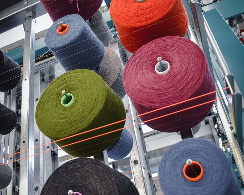 Spools of colorful yarn on a metal rack