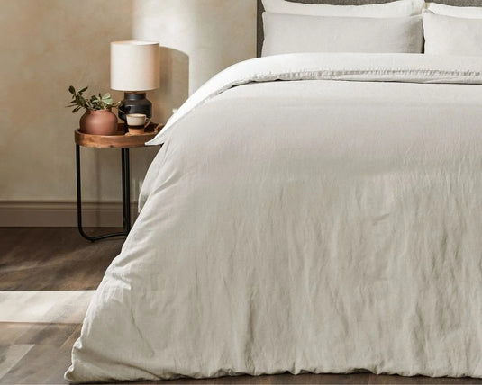 Neatly made bed with light-colored bedding in a bedroom setting.