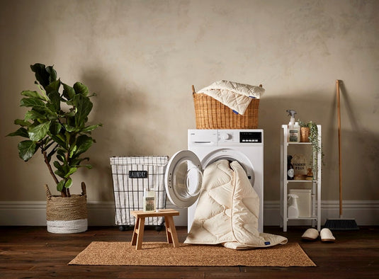 Laundry room with washing machine, dryer, and laundry basket against a beige wall.