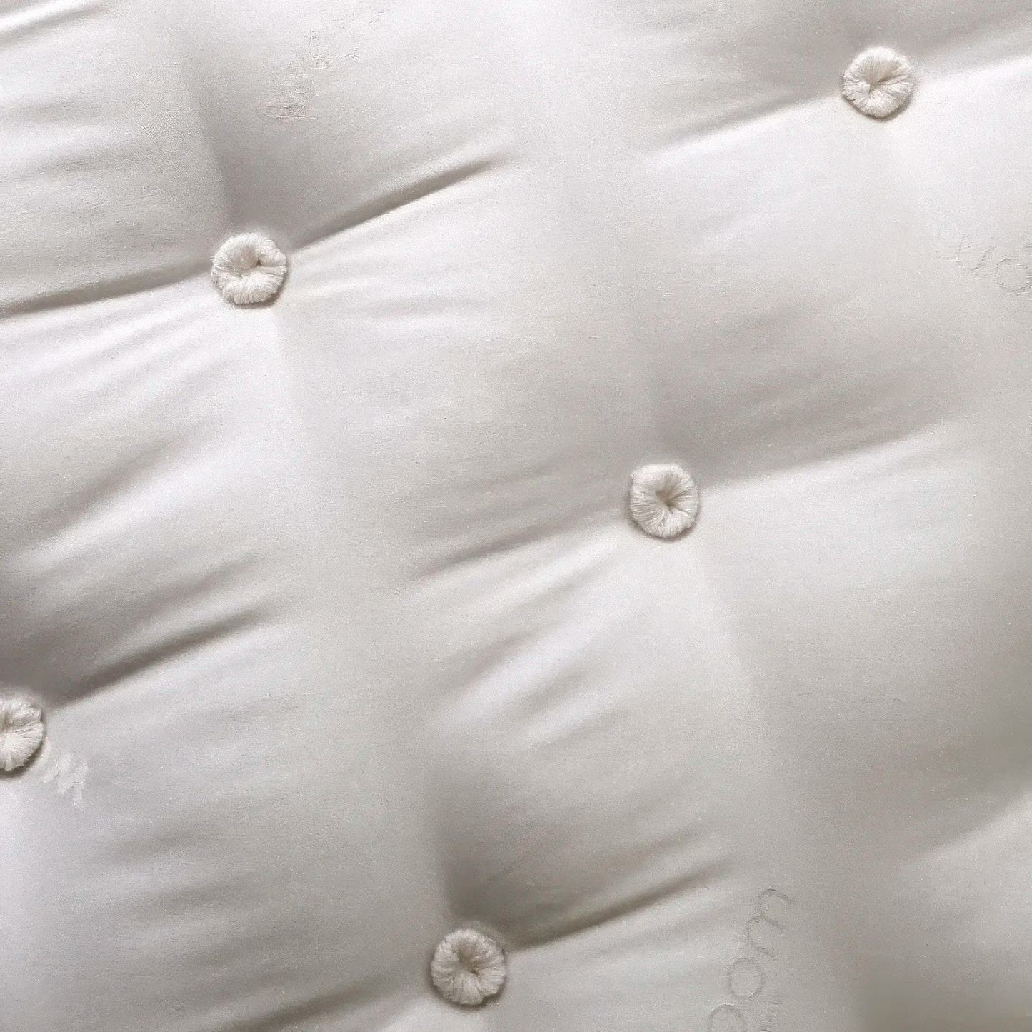 Close-up of a white quilted surface with button details