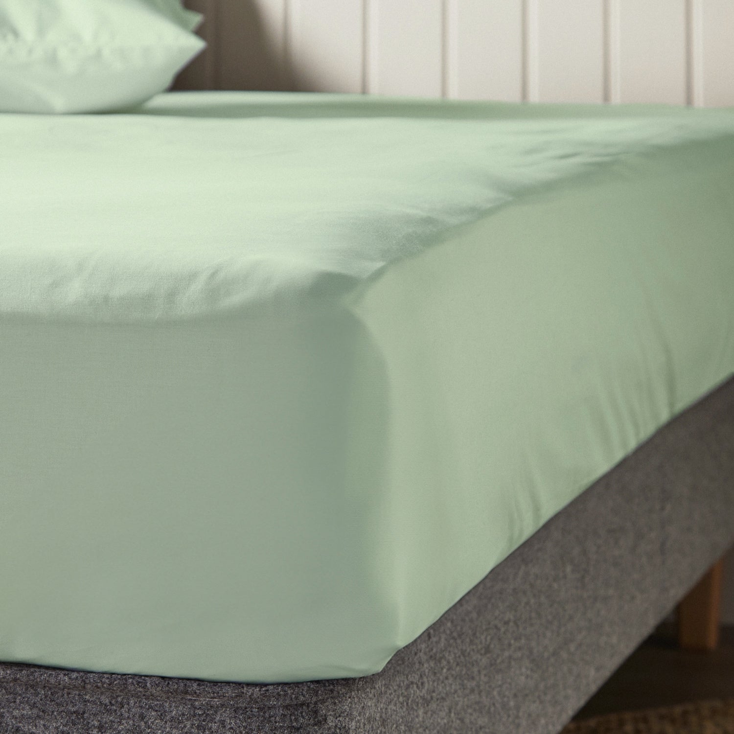 A close up of the corner of a mattress with Woolroom's Arinta Organic Cotton Fitted Sheet in Pistachio.