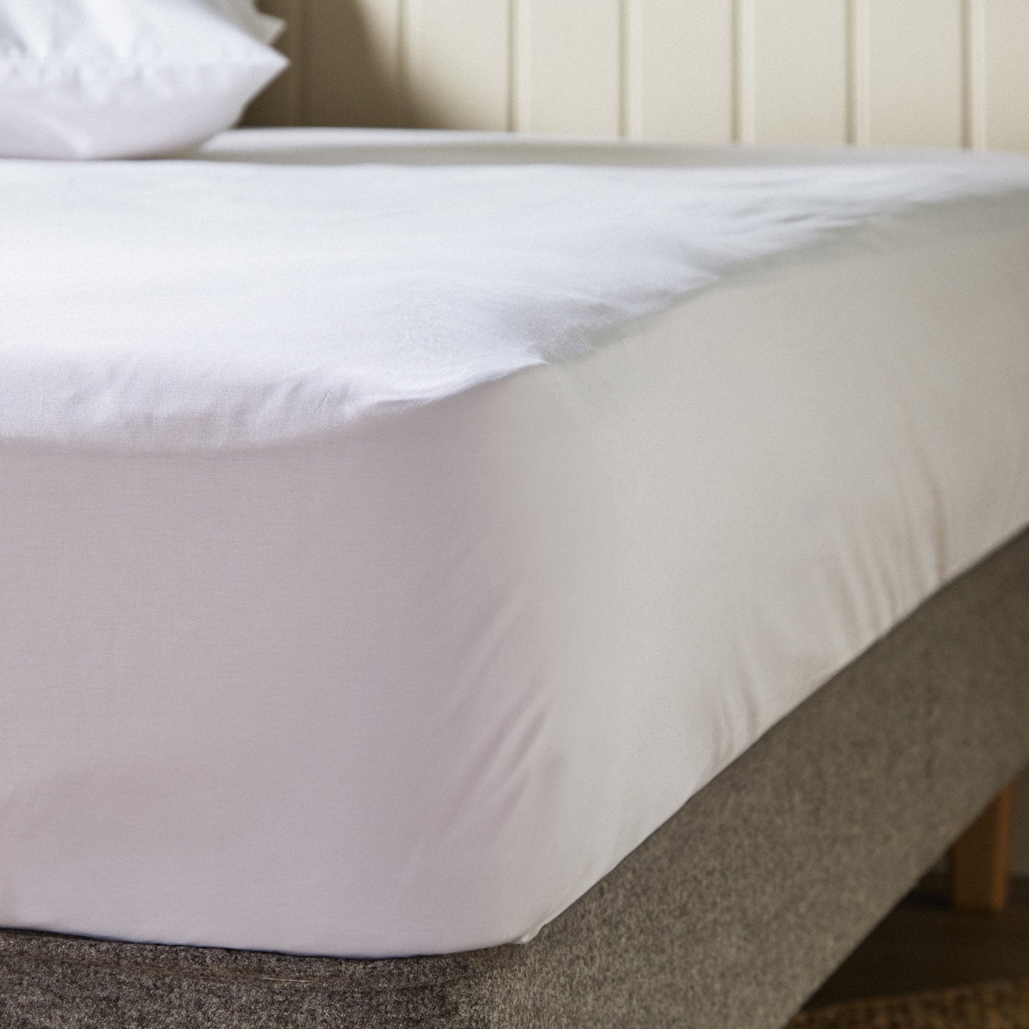 A close up of the corner of a mattress with Woolroom's Arinta Organic Cotton Fitted Sheet in White.