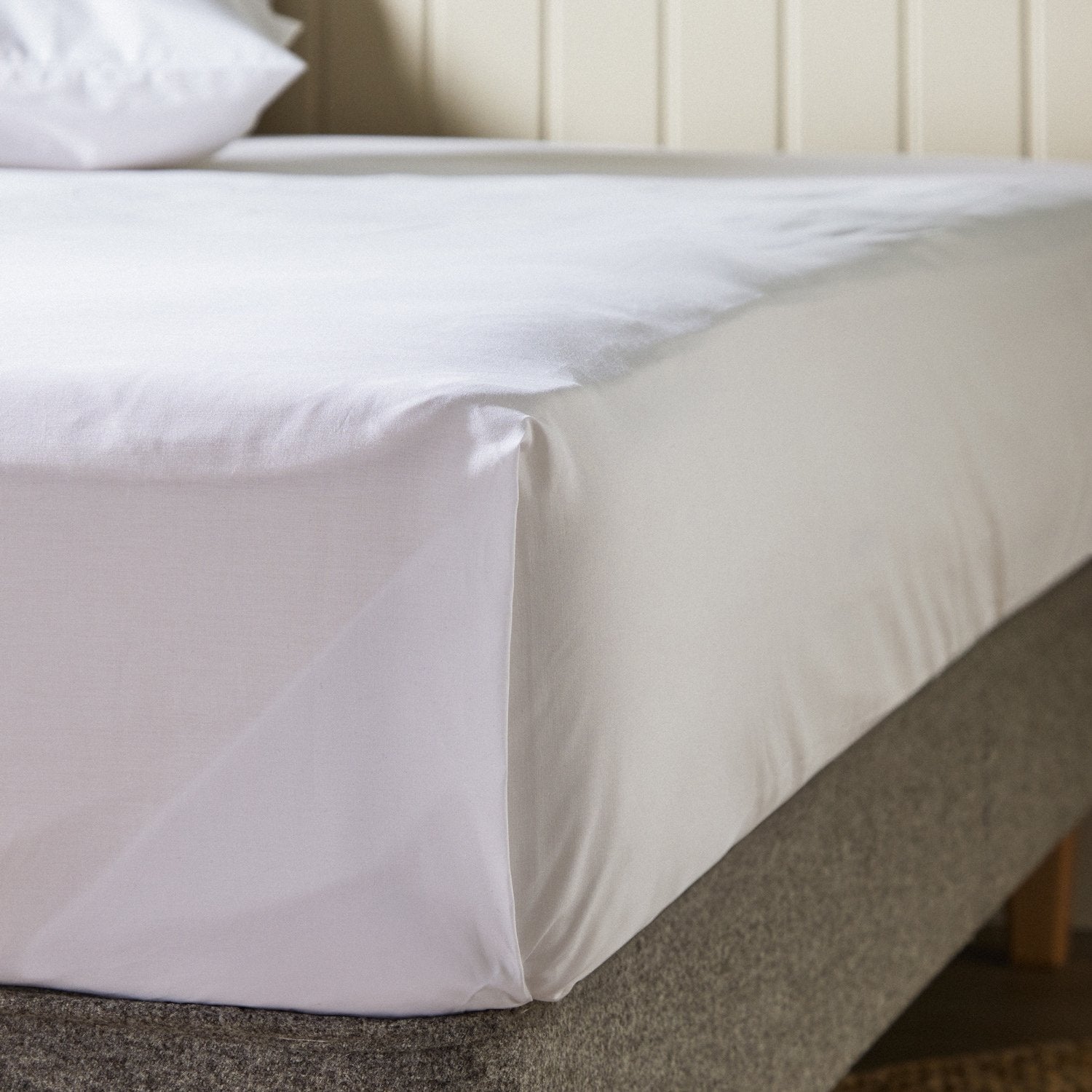 Woolroom's Arinta Organic Cotton top sheet in White draped over the end of a bed.