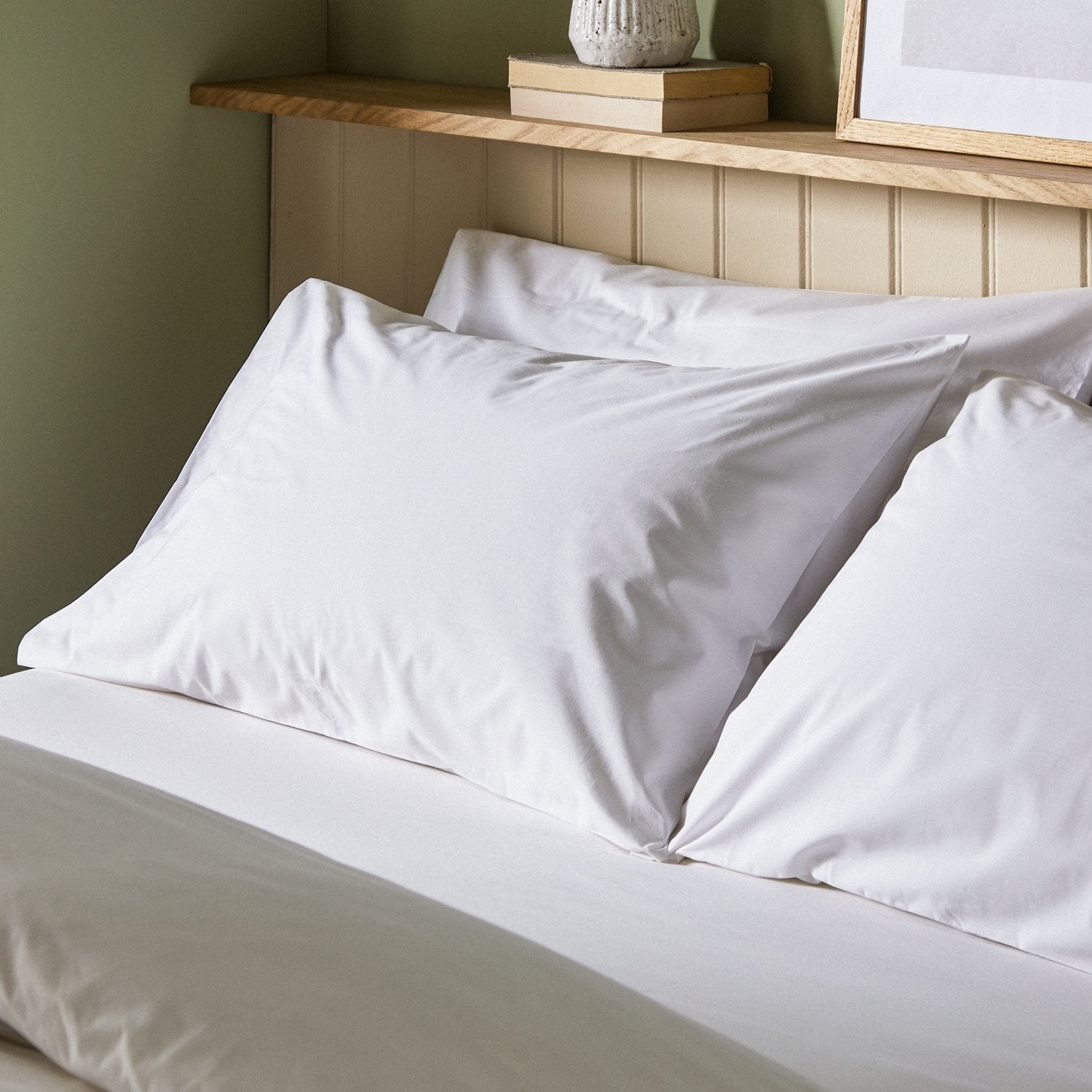 The crisp Arinta Organic Cotton Pillow Case in White on a dressed bed with four pillows.