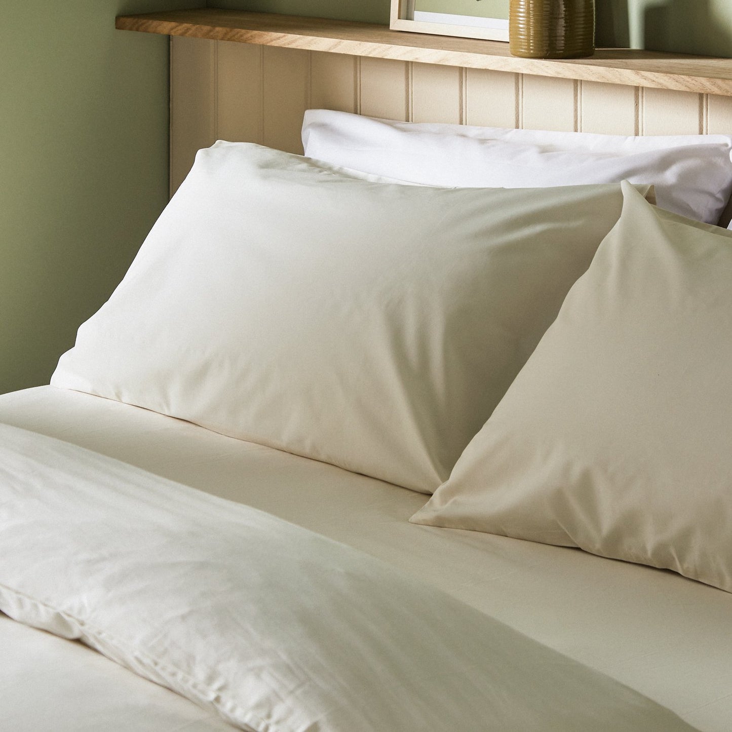 The crisp Arinta Organic Cotton Pillow Case in Vanilla on a dressed bed with four pillows.