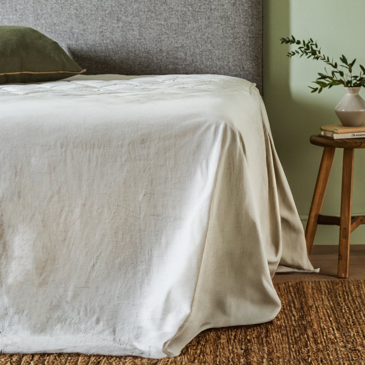 Woolroom's Mariana Linen Blend top sheet in Ivory draped over the end of a bed.
