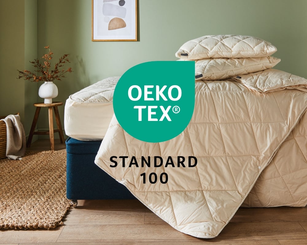 Beige quilted cover on a bed with 'OEKO-TEX Standard 100' label in a room setting.
