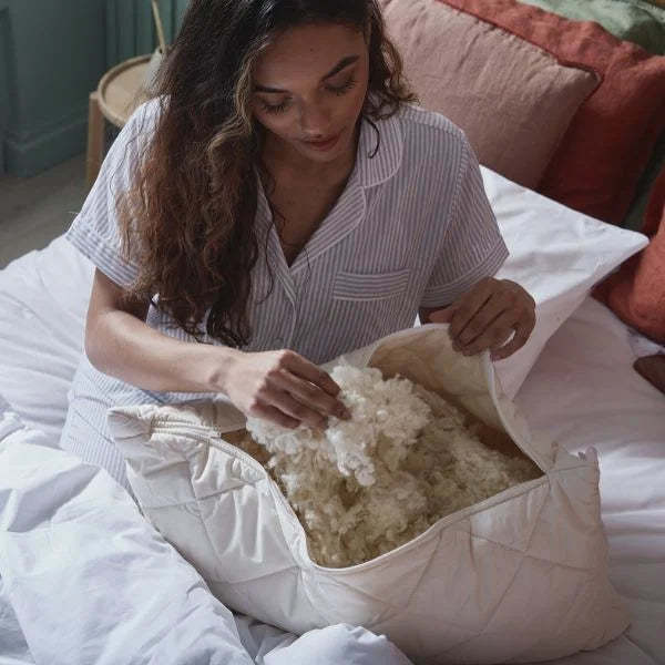 How To Adjust Your Pillow For A Great Night’s Sleep - Woman adjusting the natural wool filling of Woolroom pillow