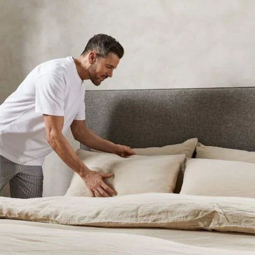Expert Tips to Reduce Allergens in Your Bedroom - man fluffing pillow on bed