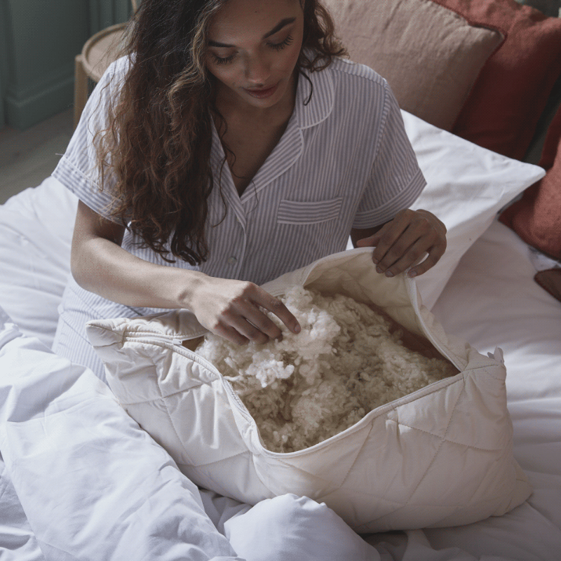 Lady fluffing up the wool inside her open pillow