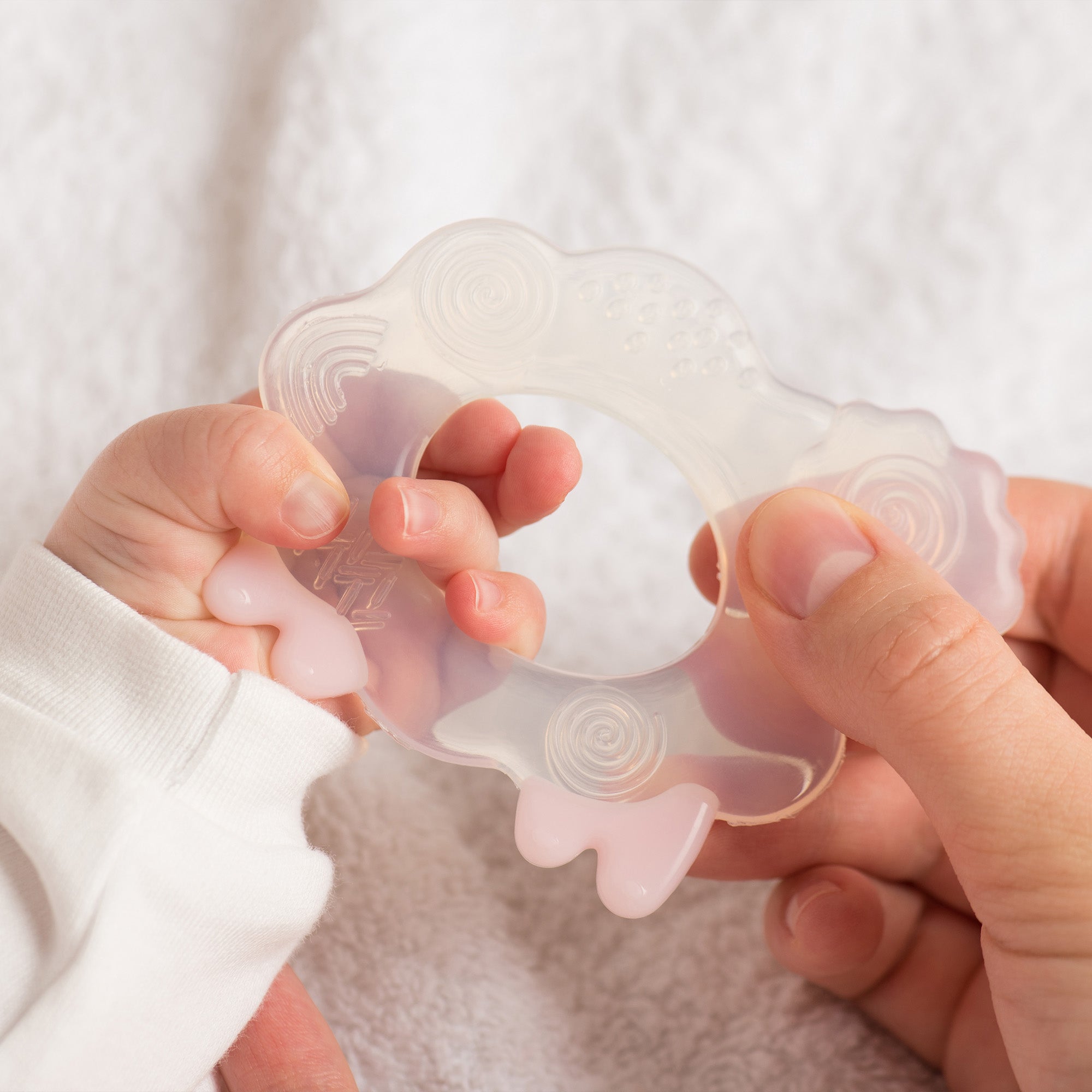 a mother and baby's hand holding a sheep shaped teething toy