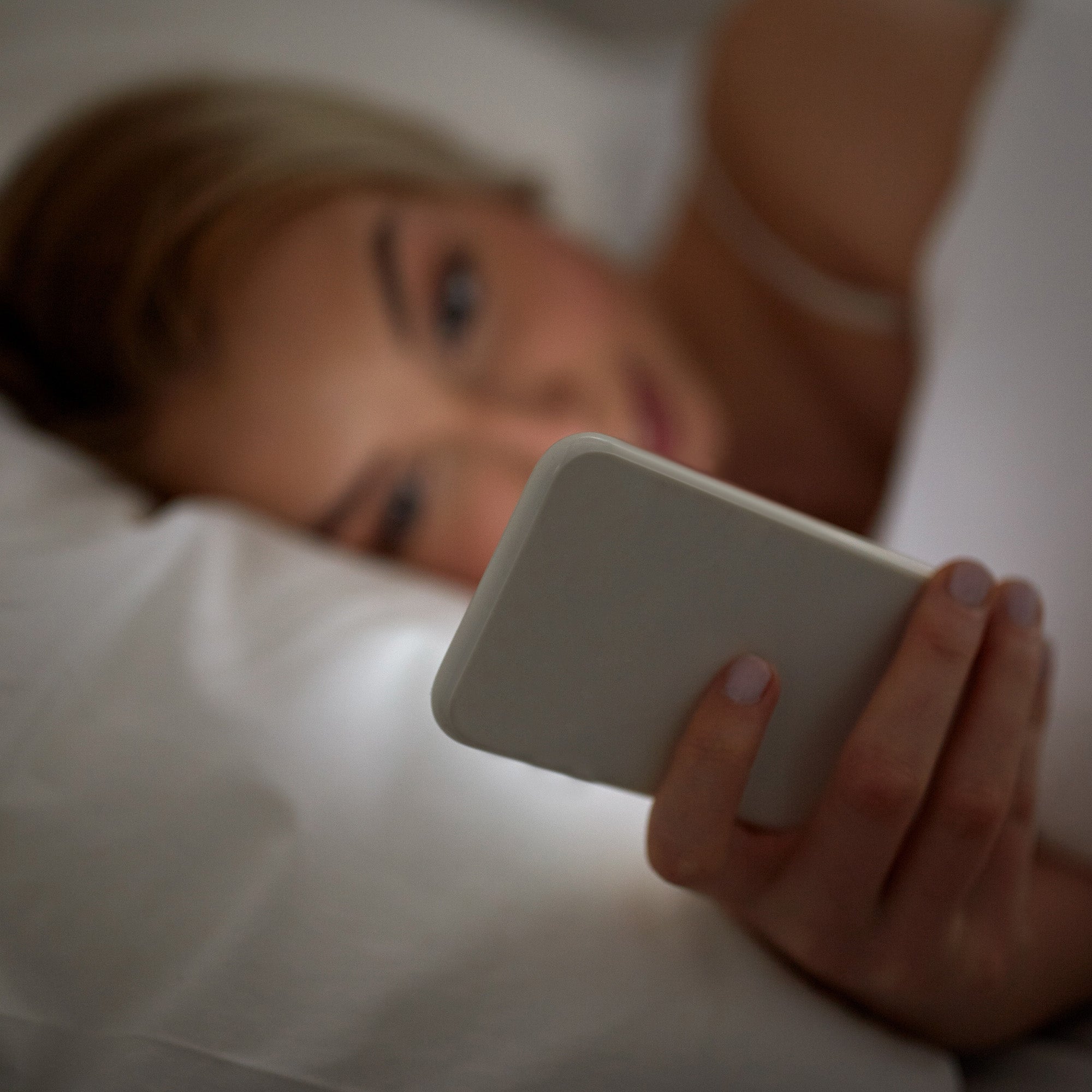 woman looking at smartphone while in bed