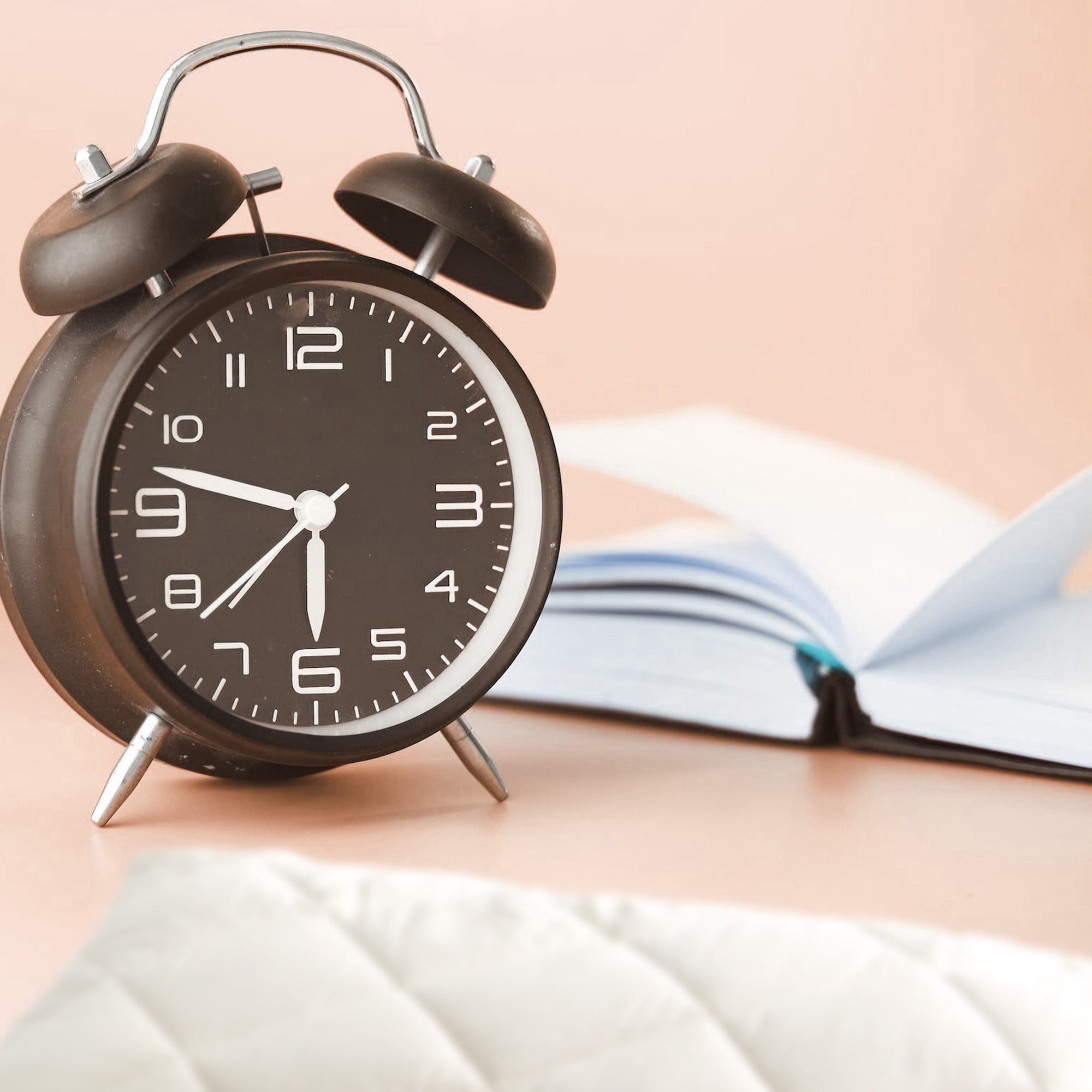 a book, alarm clock, and the edge of a wool pillow