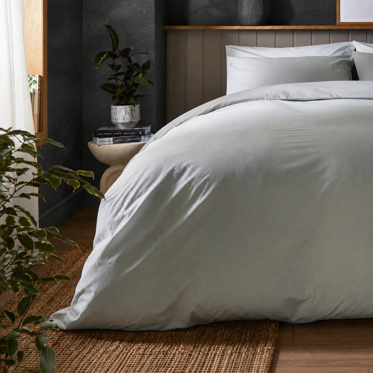 A dressed bed with Woolroom's Arinta's Organic Cotton Duvet Cover in Earl Grey has the duvet turned down and two pillows. 