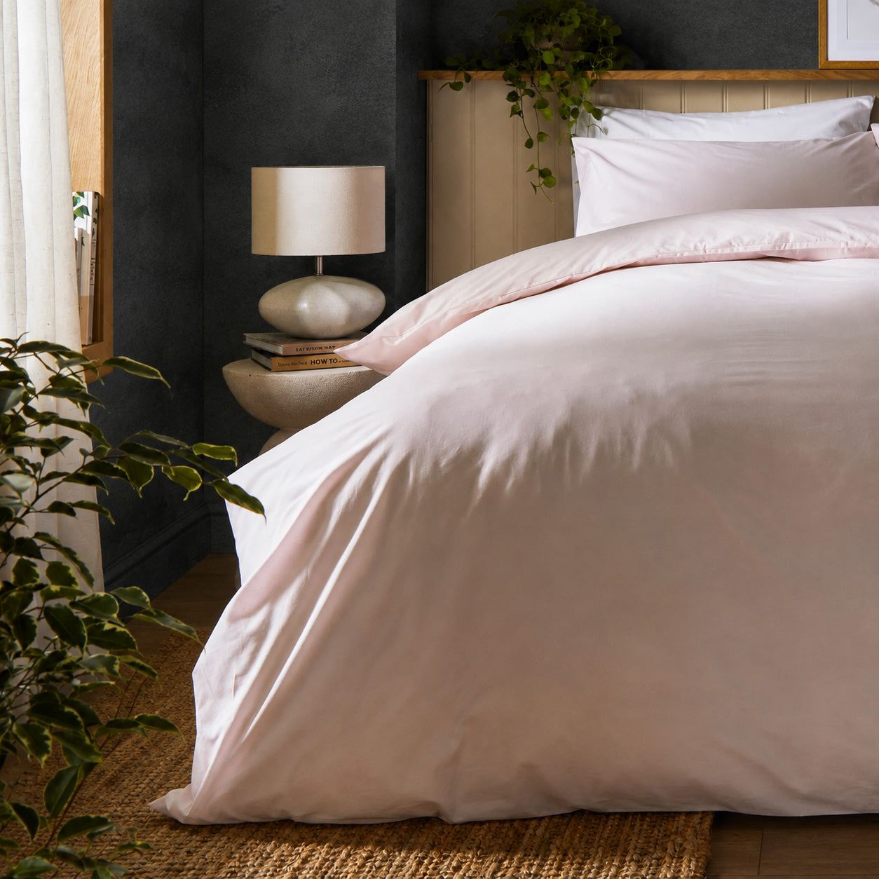A dressed bed with Woolroom's Arinta's Organic Cotton Duvet Cover in Marshmallow has the duvet turned down and two pillows. 