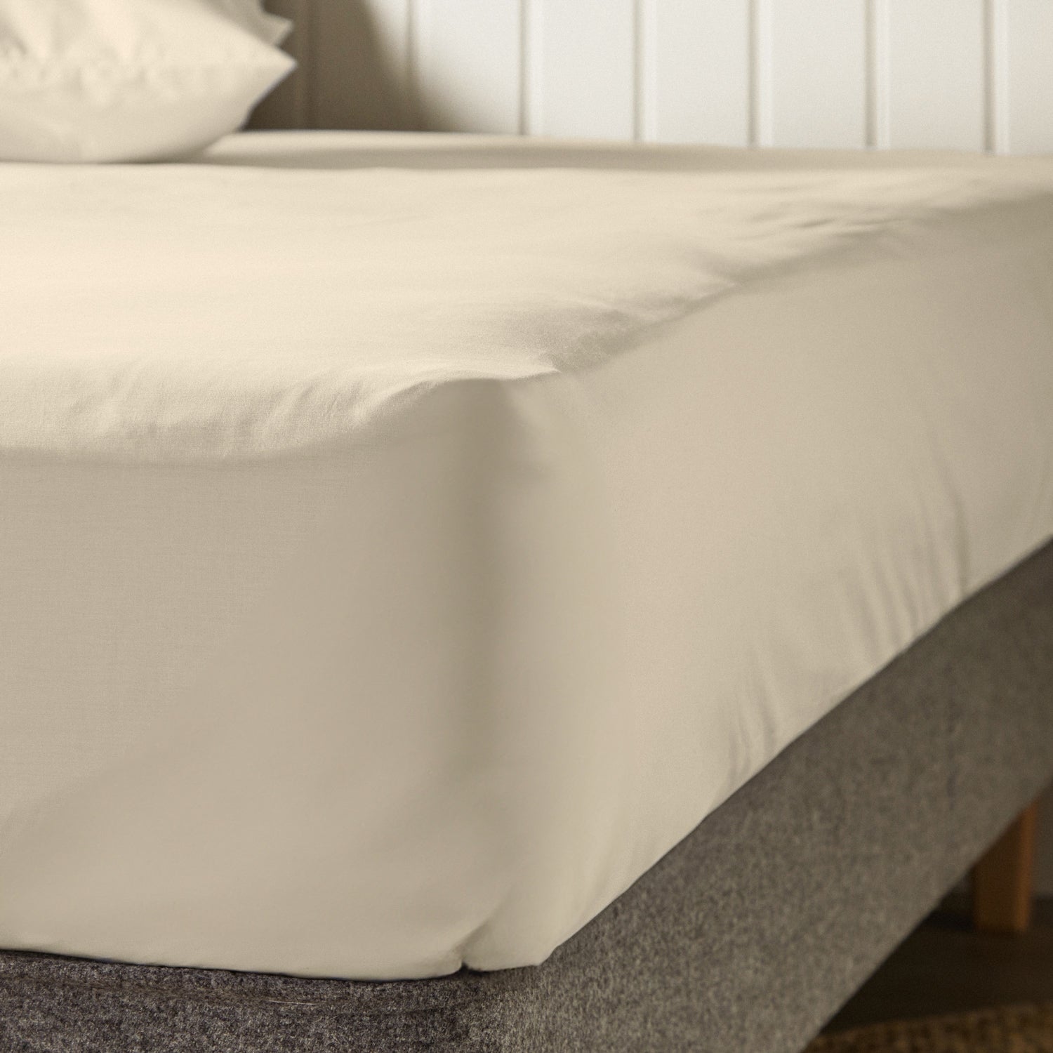 A dressed bed with Woolroom's Arinta's Organic Cotton Duvet Cover in Almond has the duvet turned down and two pillows. 