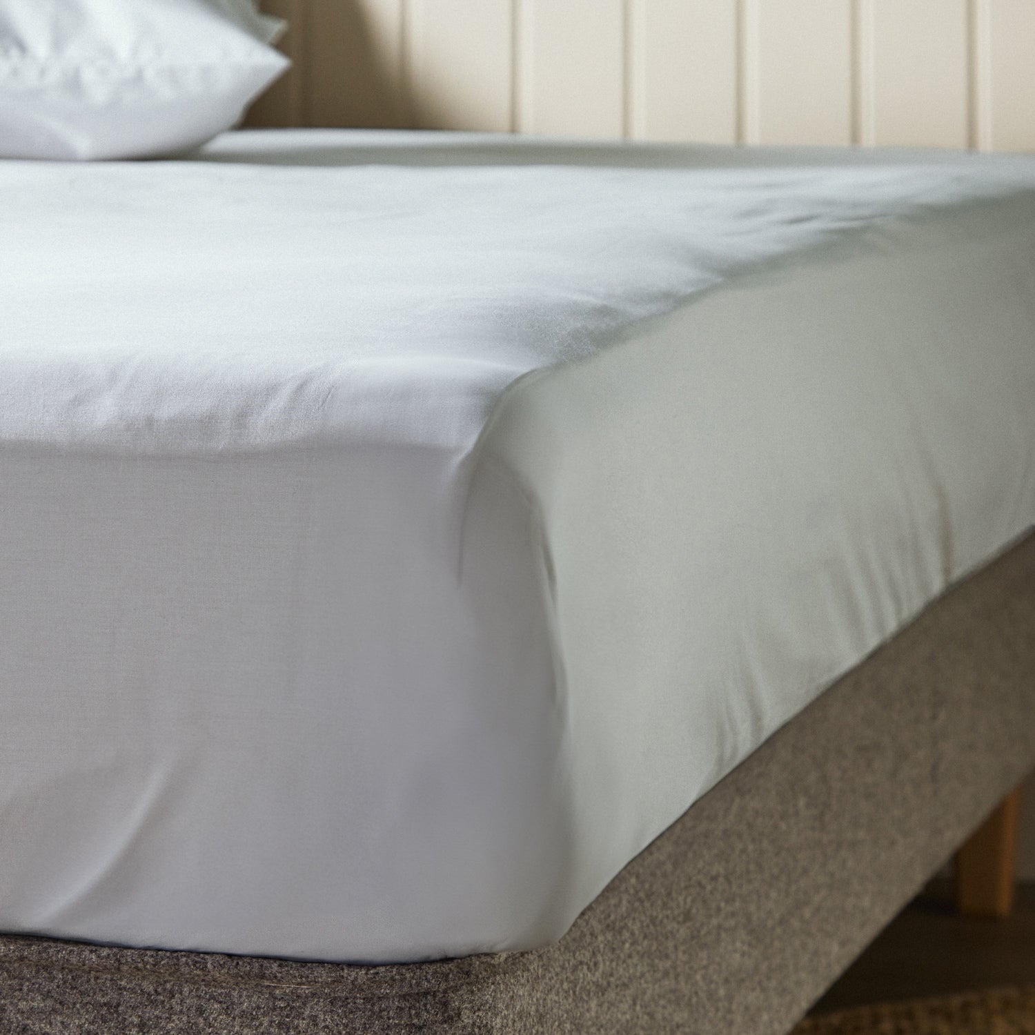 A close up of the corner of a mattress with Woolroom's Arinta Organic Cotton Fitted Sheet in Earl Grey.