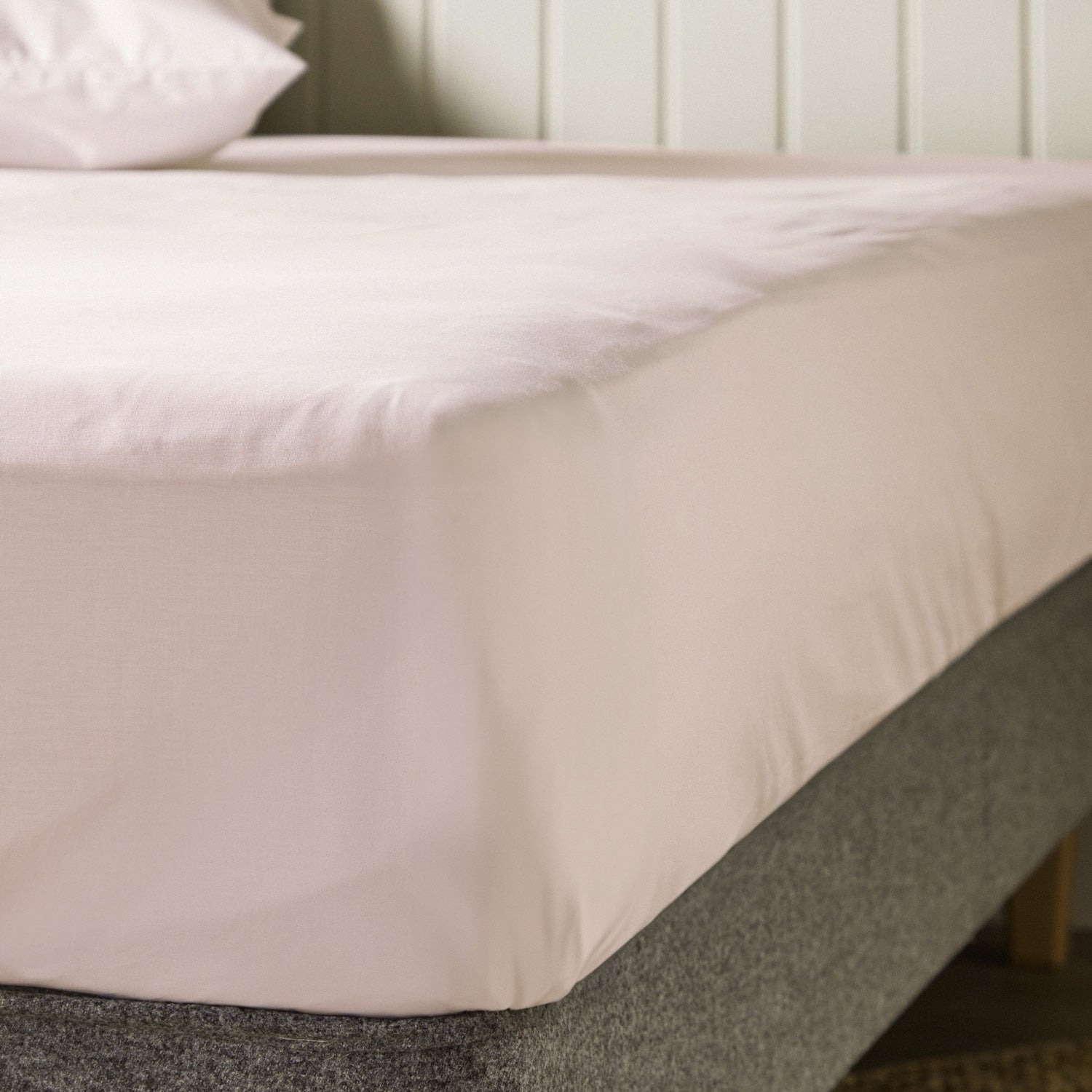 A close up of the corner of a mattress with Woolroom's Arinta Organic Cotton Fitted Sheet in Marshmallow.
