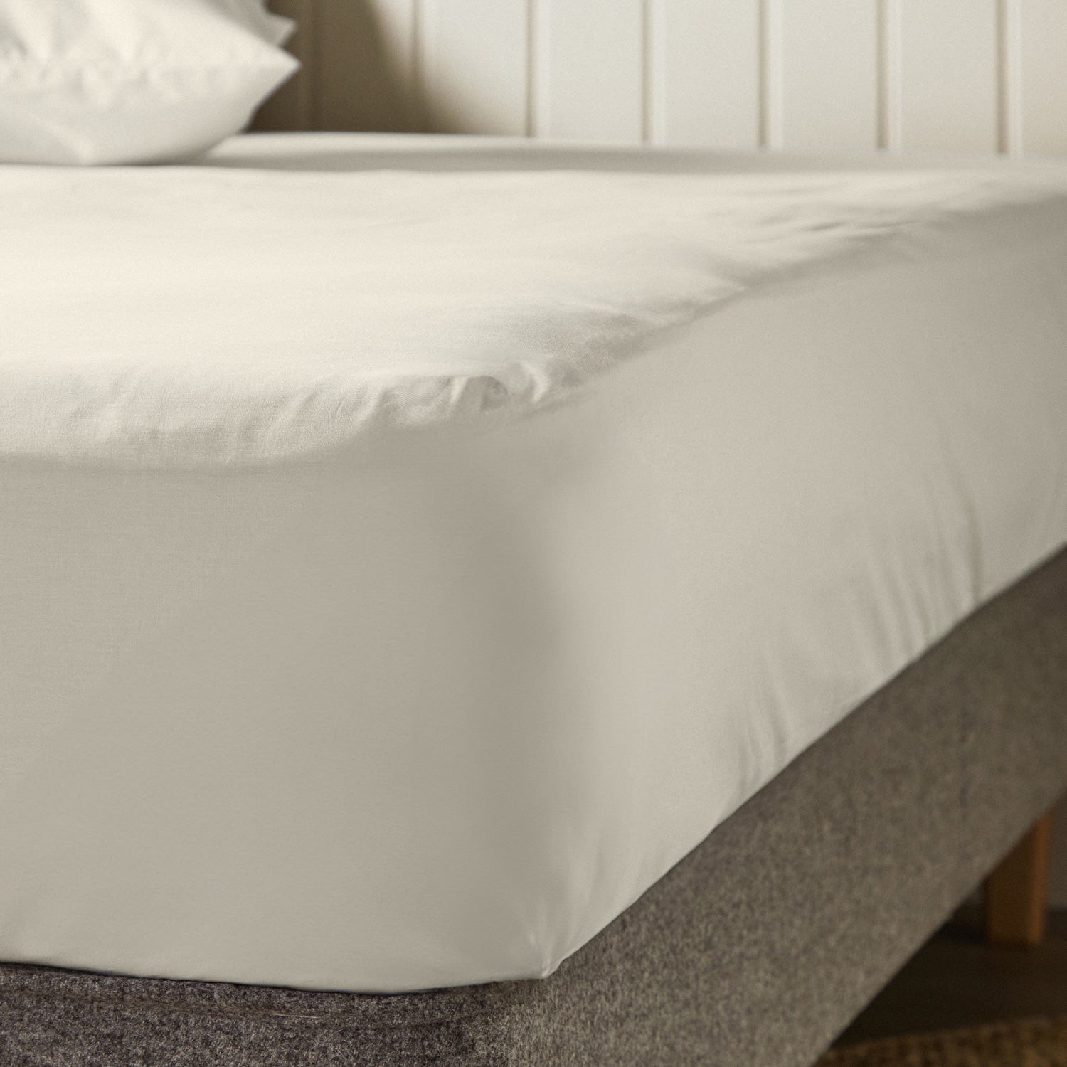 A close up of the corner of a mattress with Woolroom's Arinta Organic Cotton Fitted Sheet in Pistachio.