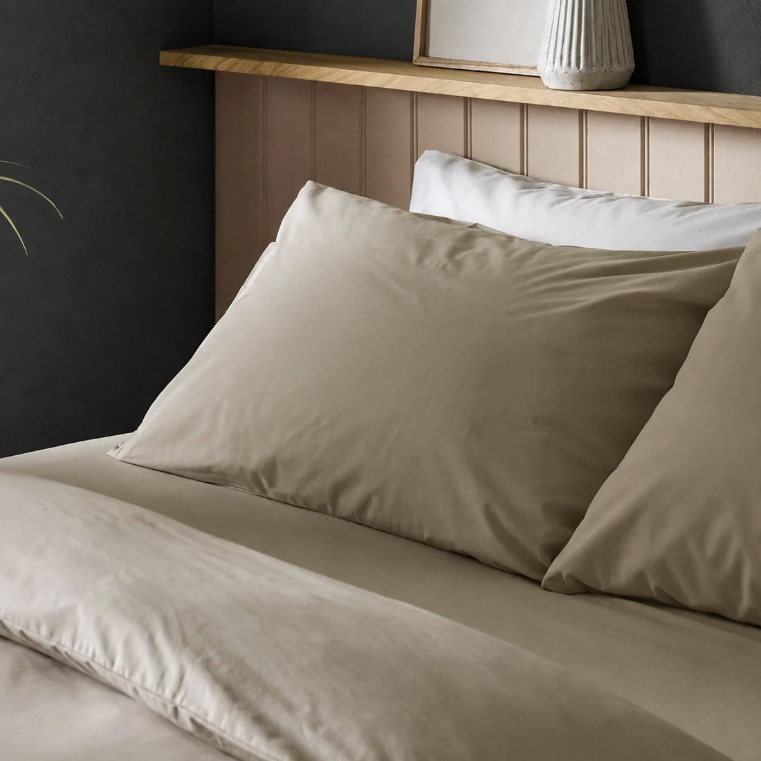 Four pillows on a dressed bed with Arinta Organic Cotton Pillow Cases in Almond.