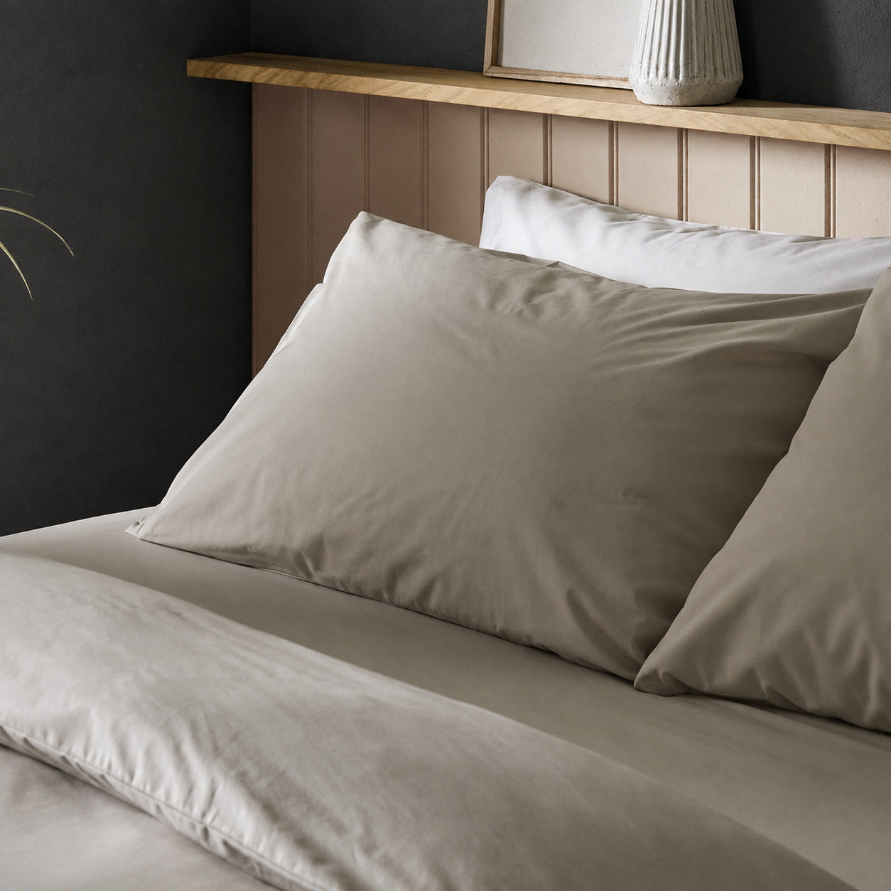 Four pillows on a dressed bed with Arinta Organic Cotton Pillow Cases in Almond.