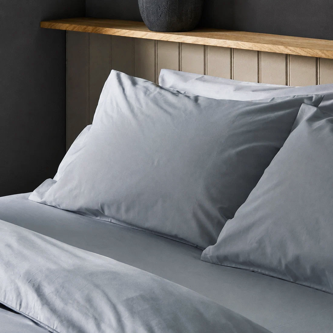 Four pillows on a dressed bed with Arinta Organic Cotton Pillow Cases in Earl Grey.