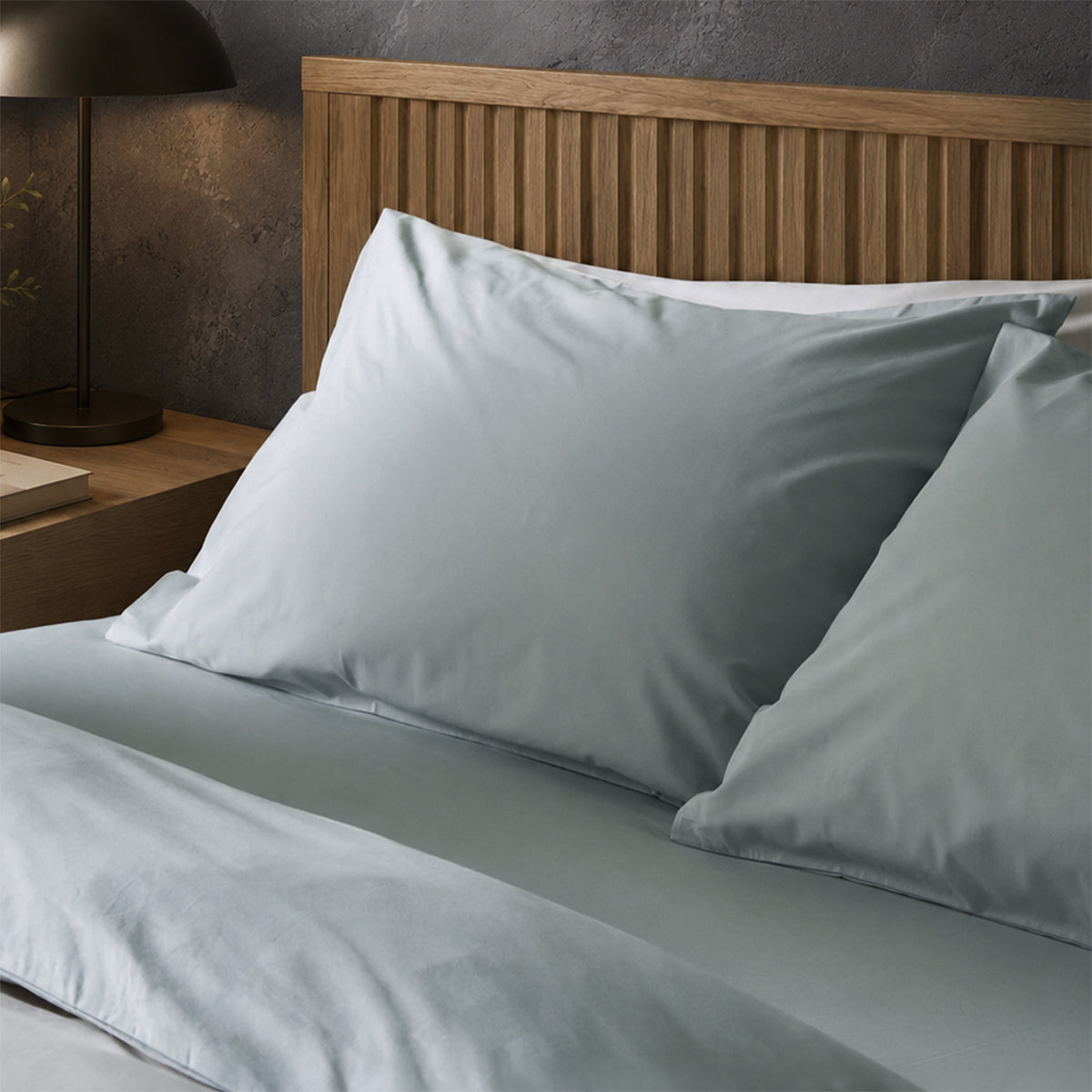 Four pillows on a dressed bed with Arinta Organic Cotton Pillow Cases in Earl Grey.