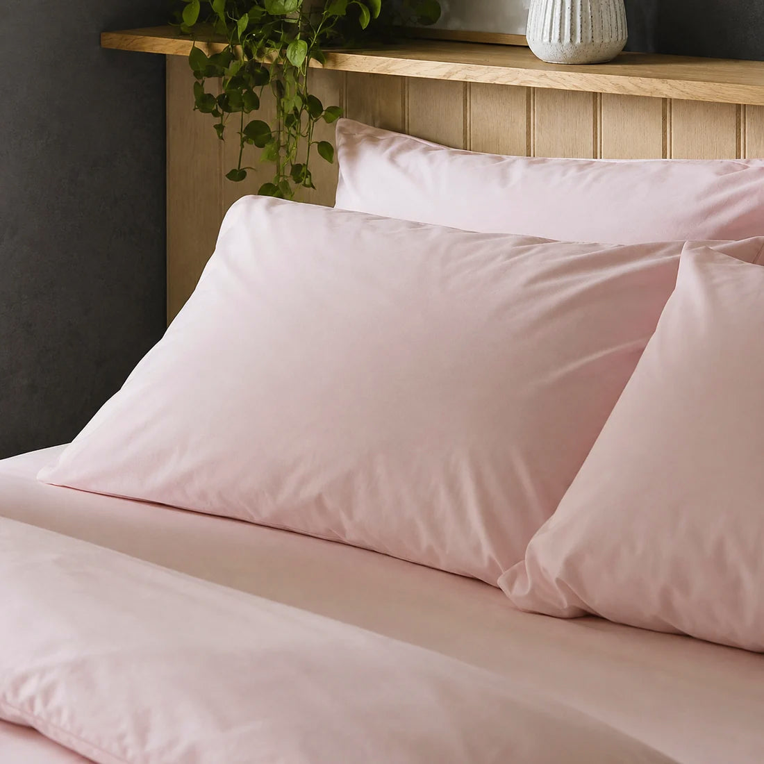 Four pillows on a dressed bed with Arinta Organic Cotton Pillow Cases in Marshmallow.