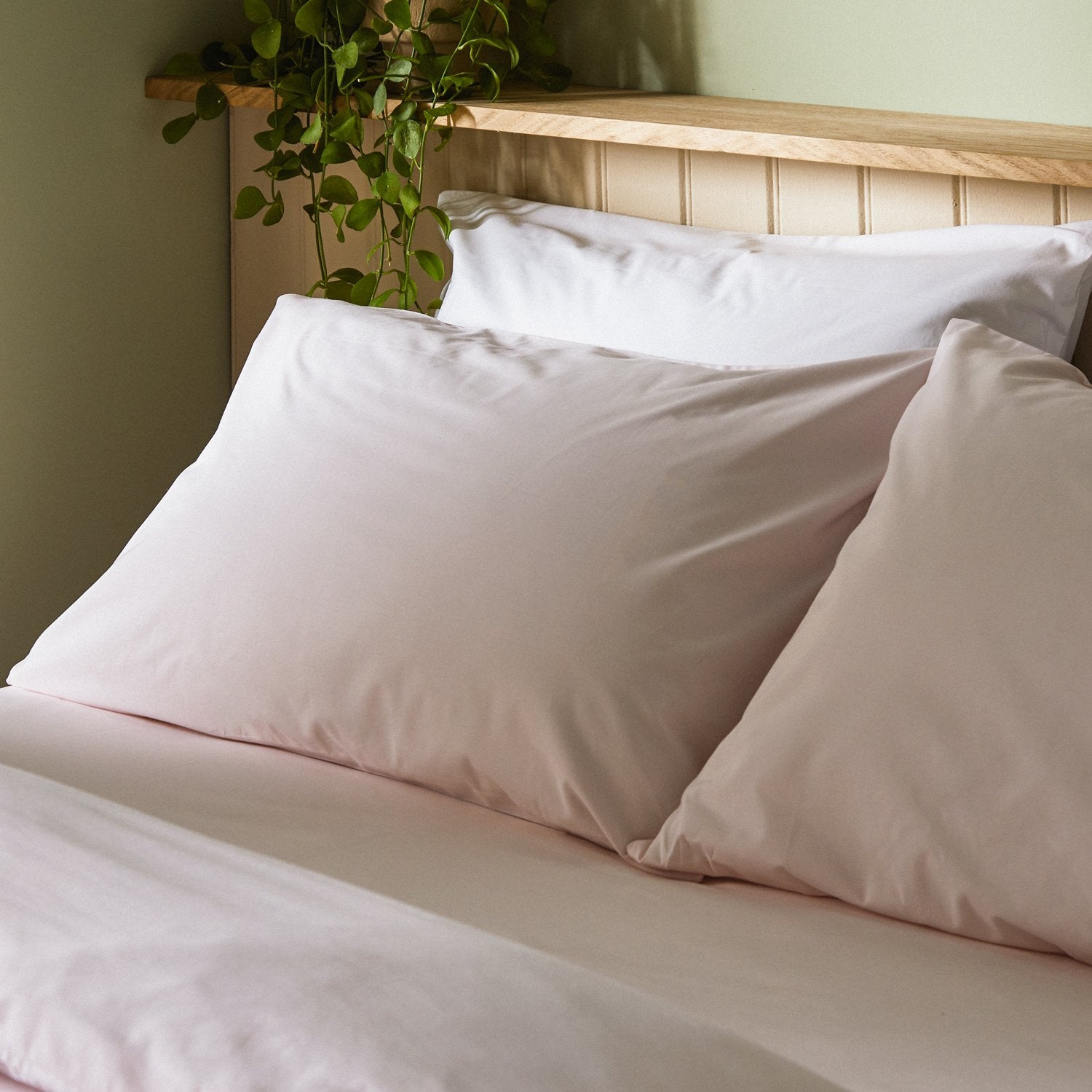 Four pillows on a dressed bed with Arinta Organic Cotton Pillow Cases in Marshmallow.