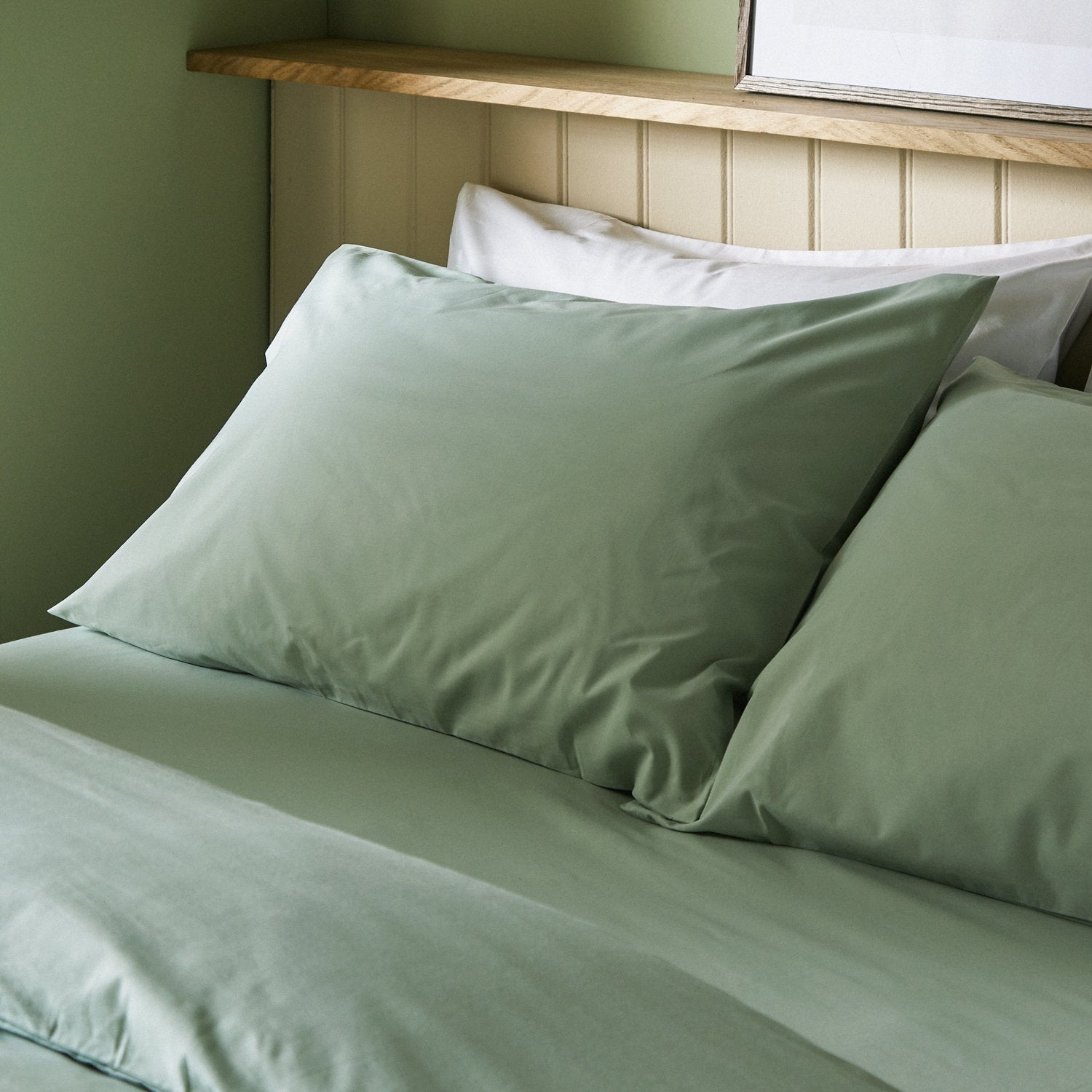 Four pillows on a dressed bed with Arinta Organic Cotton Pillow Cases in Pistachio.
