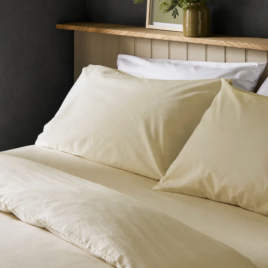 Four pillows on a dressed bed with Arinta Organic Cotton Pillow Cases in Vanilla.