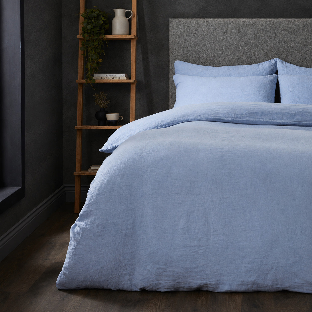 A dressed bed with Woolroom's Mariana Linen Duvet Cover in Cornflower has the duvet turned down and two pillows. 
