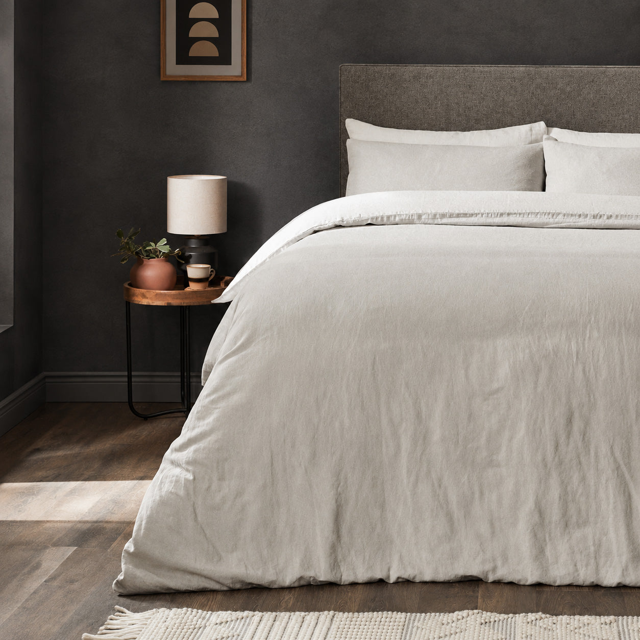 A dressed bed with Woolroom's Mariana Linen Duvet Cover in Pebble has the duvet turned down and two pillows. 
