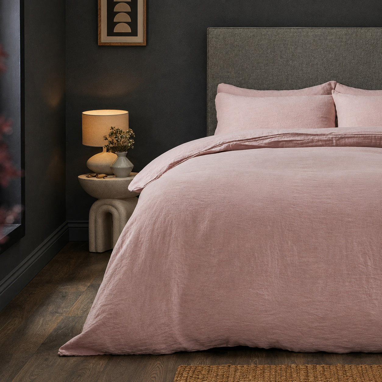 A dressed bed with Woolroom's Mariana Linen Duvet Cover in Rose has the duvet turned down and two pillows. 