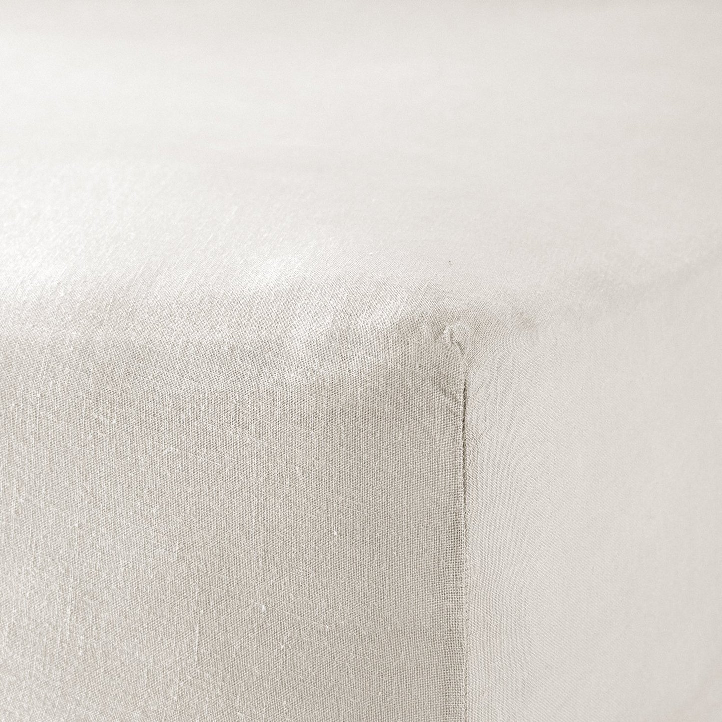 A close up of the corner of a mattress with Woolroom's Mariana Linen Blend Fitted Sheet in Ivory.