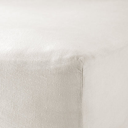 A close up of the corner of a mattress with Woolroom's Mariana Linen Blend Fitted Sheet in Ivory.