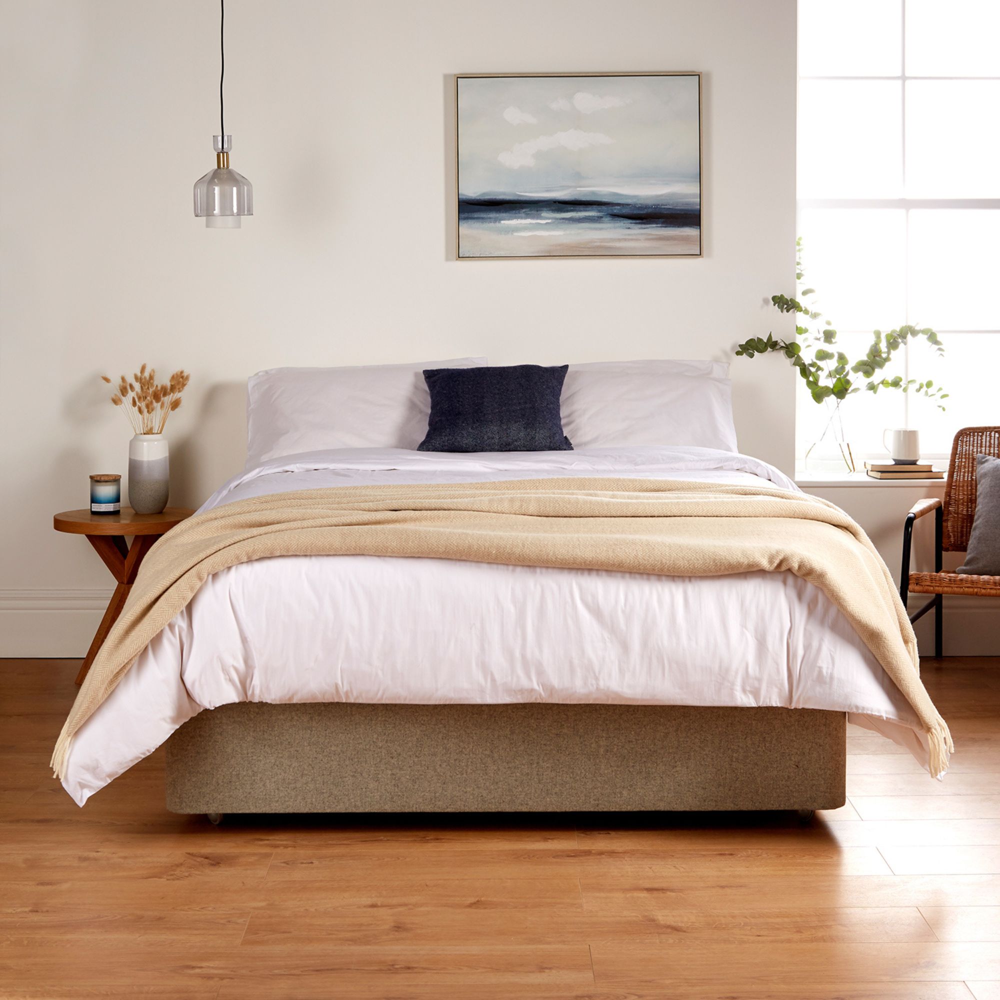 A bedroom showing the Woolroom Chianti Wide Throw in colour Sandstone draped across the foot of the bed.