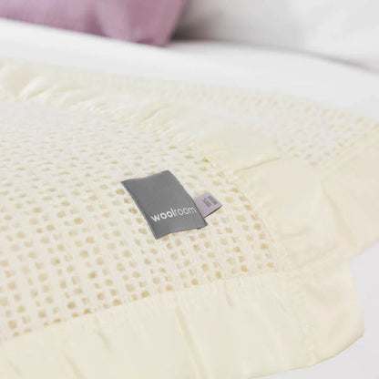 The Woolroom Ribblesdale Cellular Wool Bed Blanket in the colour Pearl has a breathable open weave texture with a satin edge.