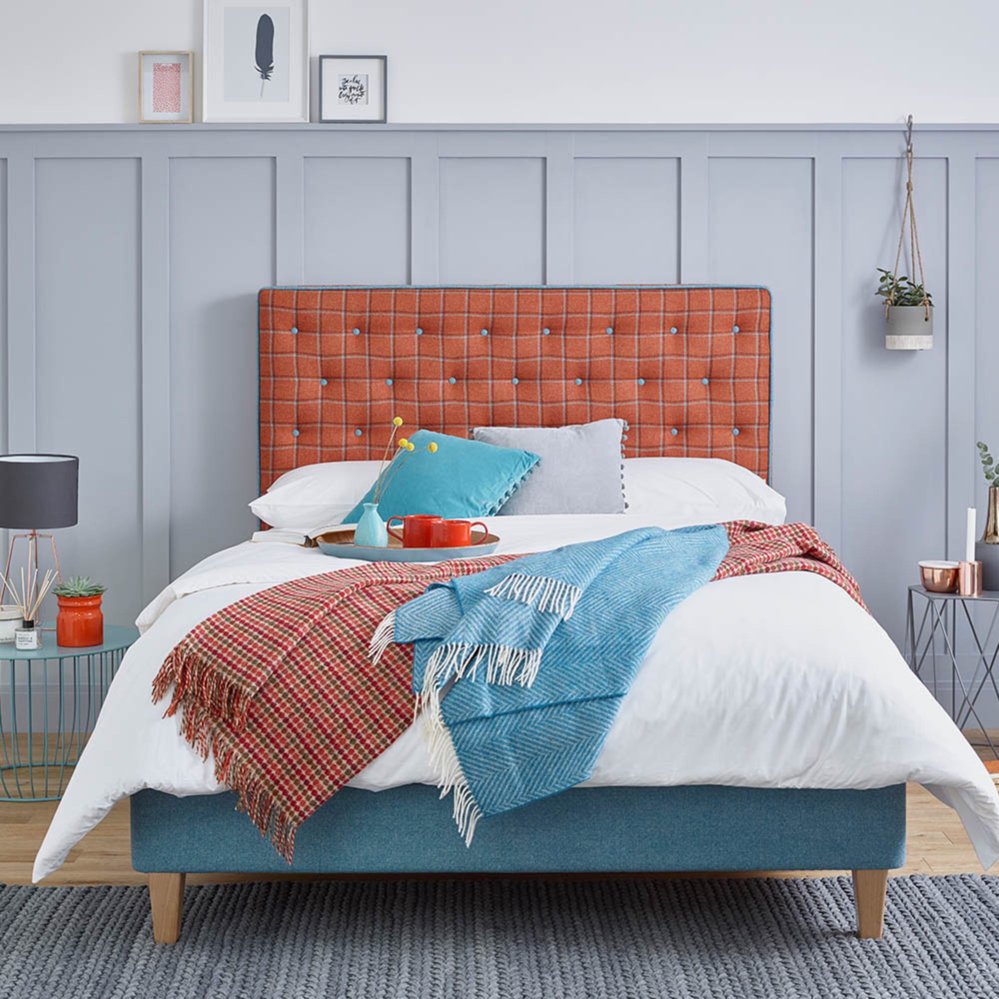 The buttoned Amelia Upholstered Bedstead in a fully custom fabric combination, dressed with throws blankets and pillows.