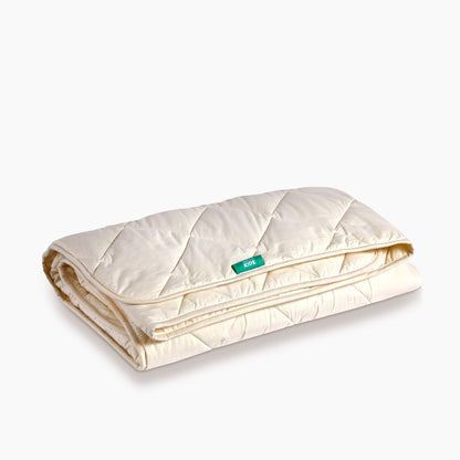 A folded Woorloom Deluxe Washable Wool Kids Duvet, without a cover showing the unbleached cotton outer.