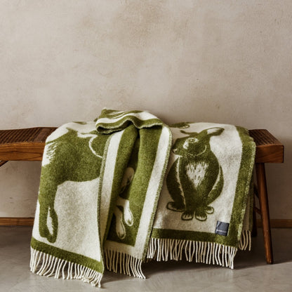 The playful Wild and Wool Rabbit Wool Throw in Moss with white fringe belongs to the Woolroom animal throw collection.