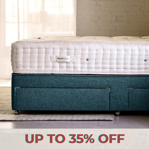 A man hand teasing wool on top of a mattress, in Woolroom's factory