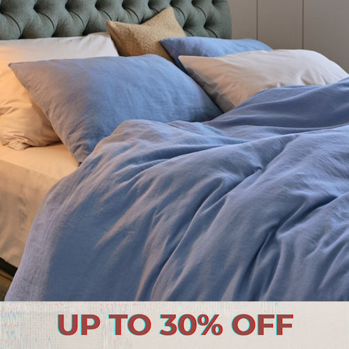 Bundle of neatly folded green bed linen, sat on a wooden bench.