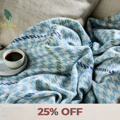 A collection of blue, green, red, beige and yellow wool throws draped over a wooden banister in a home.